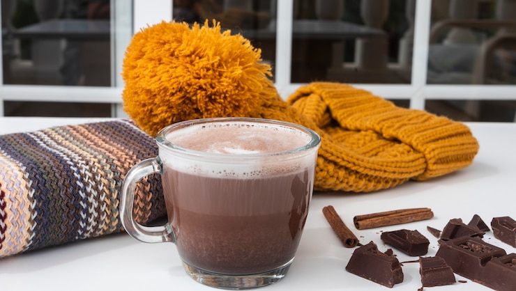 Photo 白い背景の上のホットコーヒーカプチーノとガラスカップのクローズアップテーブルの上の冬のアクセサリー