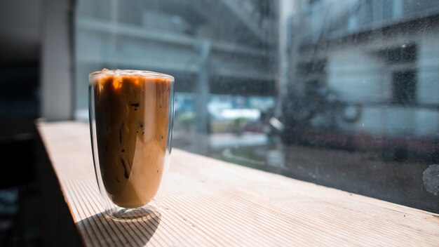 Photo closeup glass of iced coffee with milk on the table