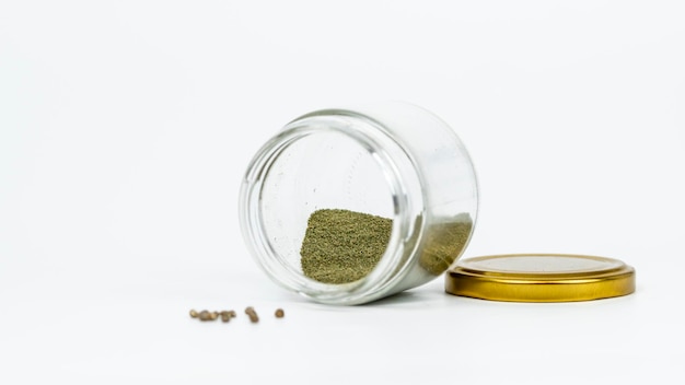 Closeup of glass jar with hashish and cannabis seeds isolated on white background