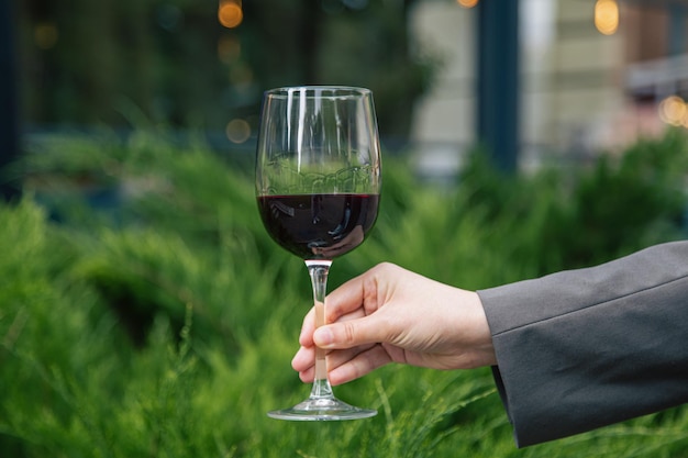 Closeup a glass of red wine against the background of green bushes