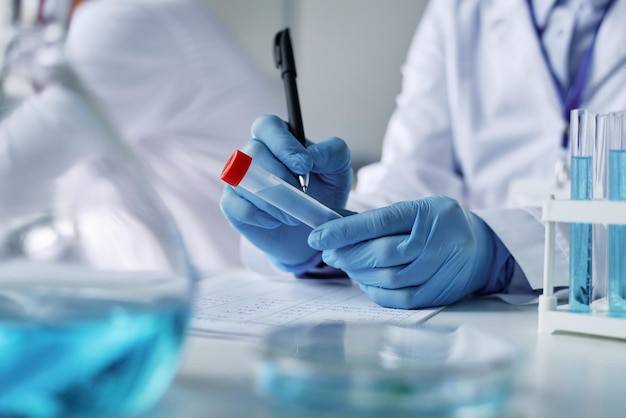 Closeup of gloved hands of clinician with pen writing down sample name