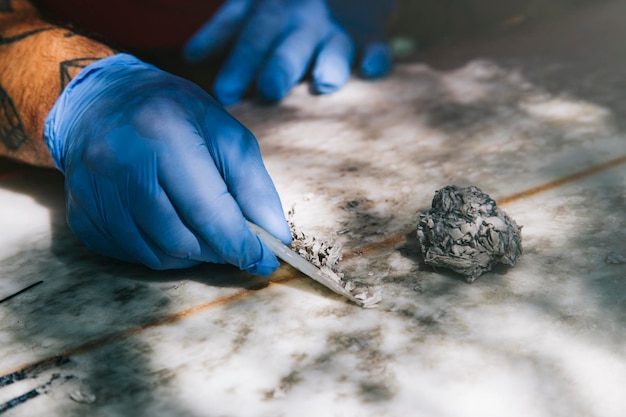 Closeup of gloved hands removing old wax with a wax comb