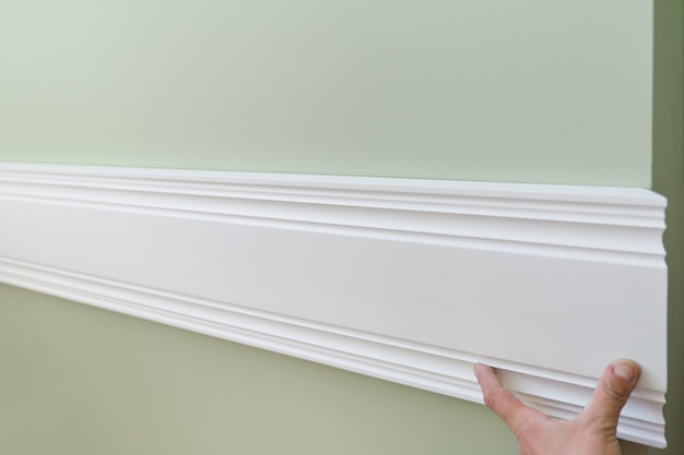 Primo piano di incollaggio del pannello della plancia dipinto bianco di legno sulla parete