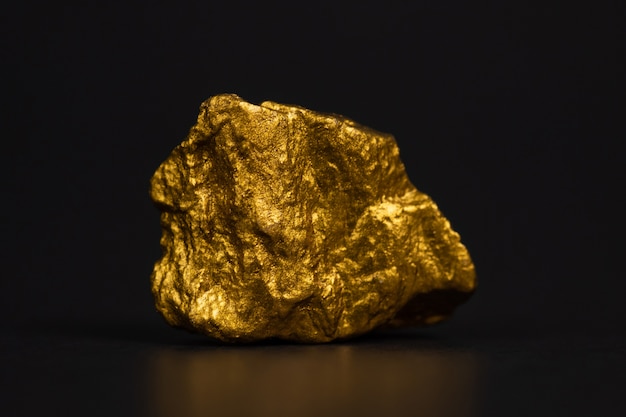 Primo piano della pepita di oro o minerale di oro sul nero