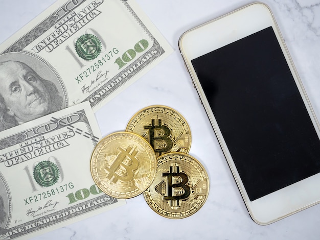 Closeup golden bitcoin with phone and dollar and pen top view crypto money concept