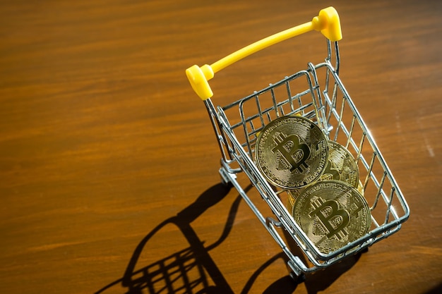 Closeup of Golden bitcoins or cryptocurrency coin or symbols in shopping cart on table Future currency concept