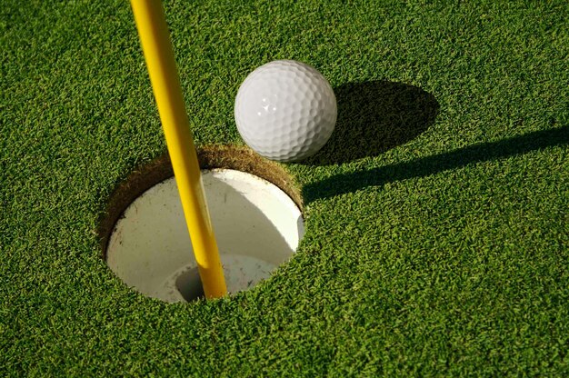 Closeup of golf course green flag pin and ball