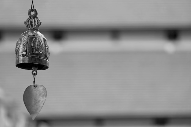 Closeup a Gorgeous Decorative Brass Wind Chime of Buddhist Temple against Blurry Roofs of the Cloister