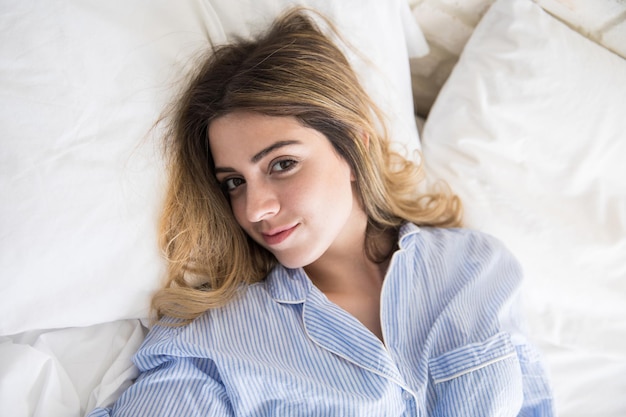 Closeup of a gorgeous young Hispanic woman lying on her bed wearing pajamas