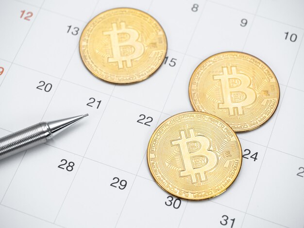 Closeup gouden bitcoin en pen op kalender bovenaanzicht