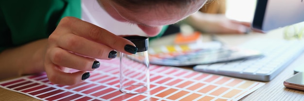 Closeup of graphic designer looking at colors samples through loupe woman choosing proper