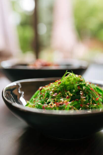 Closeup green chuka seaweed salad in black bowl