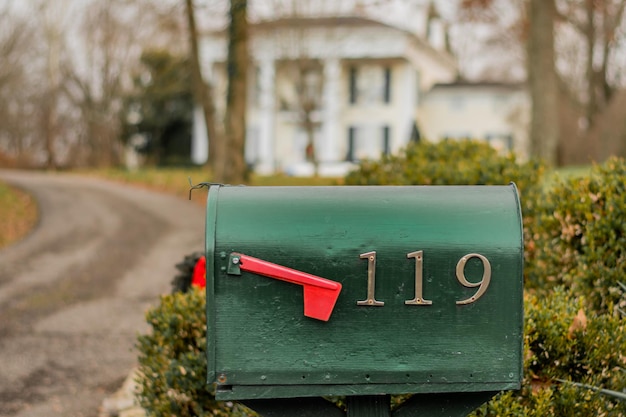 Photo closeup of the green mailbox in the street with address numbers.