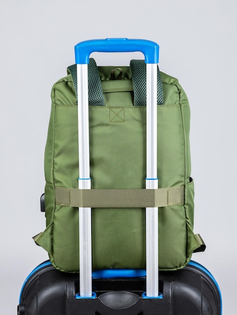 쉽게 여행할 수 있도록 여행 가방 손잡이에 얹을 수 있는 녹색 남성용 백팩을 닫습니다.