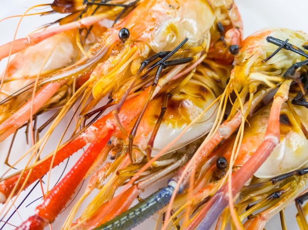 Foto primo piano del gambero d'acqua dolce gigante alla griglia sul piatto di plastica bianco nella vista frontale del ristorante di pesce con lo spazio della copia