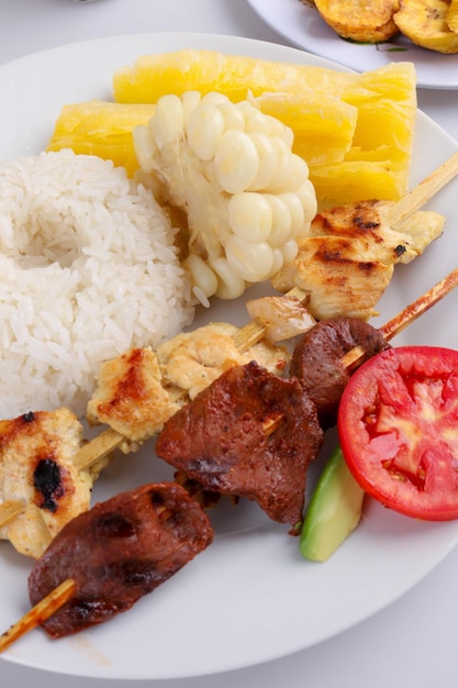 Closeup of the grilled meat on the skewer with rice and veggies on a plate