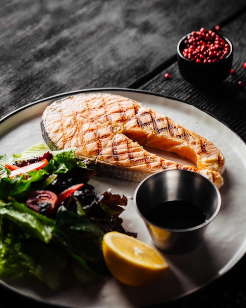 Closeup on grilled salmon steak with green salad