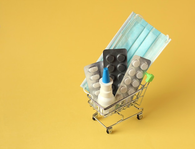 Closeup grocery cart full of medicines on yellow background