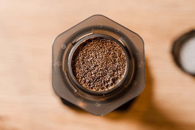 Closeup ground coffee with hot water in aeropress top view Process of aeropress alternative method brewing coffee Pouring hot water over roasted and ground coffee beans in aeropress