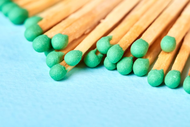 Closeup of a group of matches with green heads on a blue background