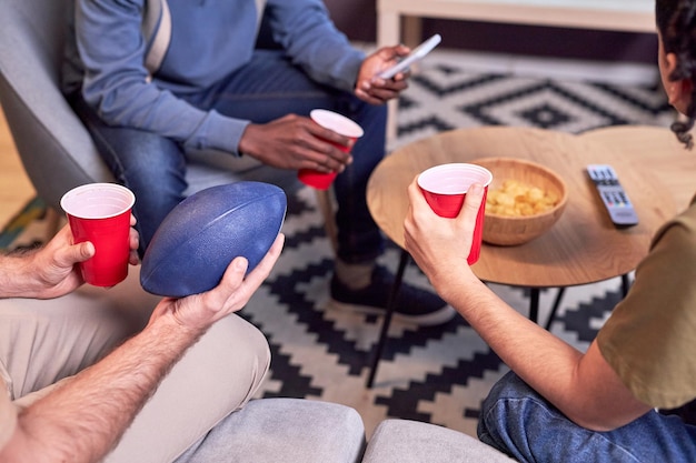 Closeup at group of sports fans watching football match and drinking beer