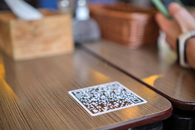 Closeup of guest hand ordering meal in restaurant while scanning qr code with mobile phone for online menu.