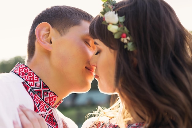 Closeup of a guy and girl kiss in embroidered clothing nature