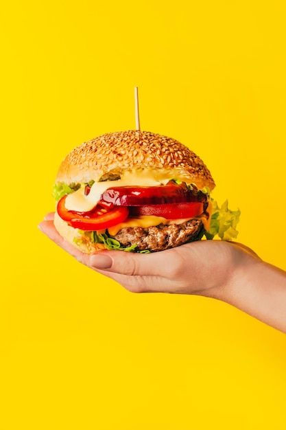 Foto close-up di un hamburger in mano di una donna su uno sfondo bianco