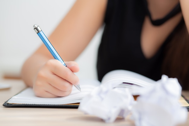 Idea di pensiero dello scrittore asiatico della donna della mano del primo piano e scrivere sul taccuino