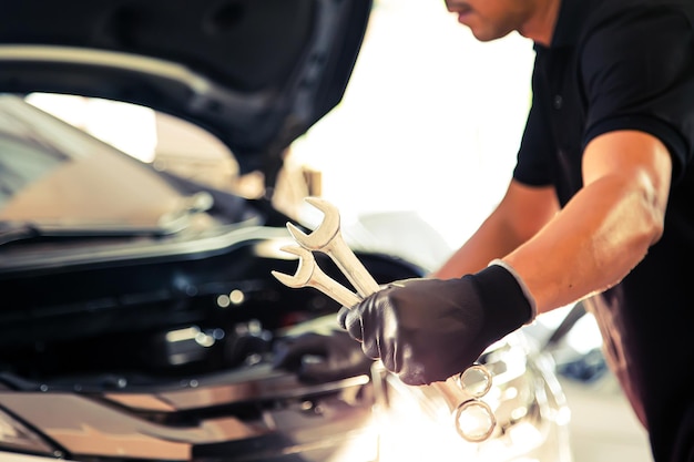 Closeup hand auto mechanic using the wrench to repairing car engine problem