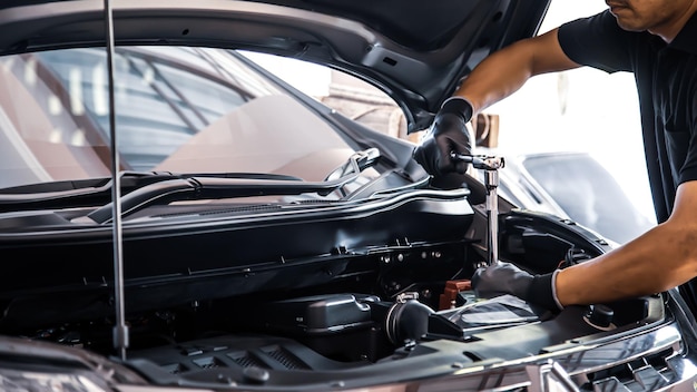 Closeup hand auto mechanic using the wrench to repairing car engine