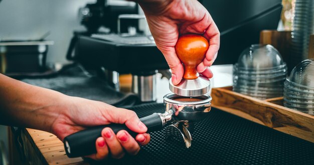 탬퍼를 사용하여 수동 프레스 그라운드 커피로 커피를 만드는 핸드 바리스타 카페의 클로즈업