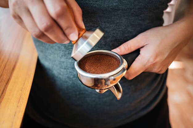 Closeup of hand Barista cafe making coffee with manual presses ground coffee using tamper