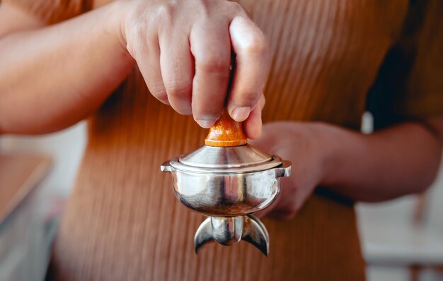 Photo closeup of hand barista cafe making coffee with manual presses ground coffee using tamper