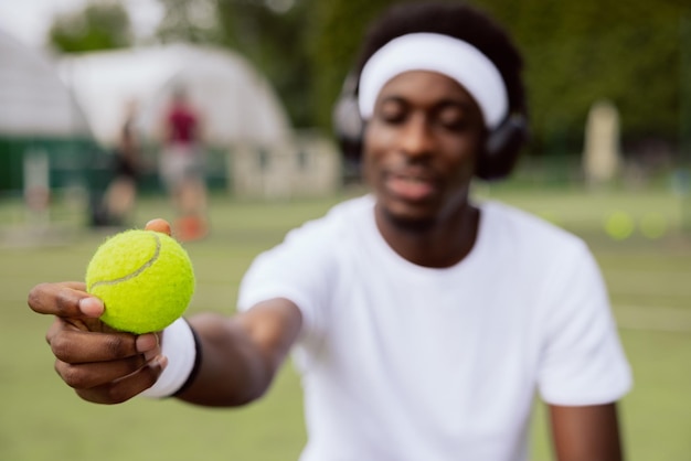 Closeup of the hand of boy of african appearance holding yellow tennis ball tennis player is sitting