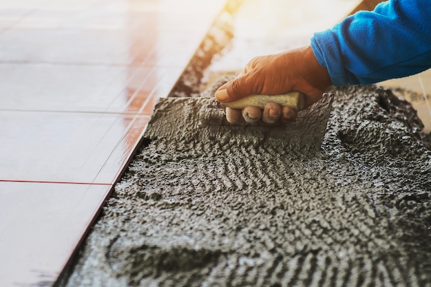 Closeup hand construction worker laying tile on floor 