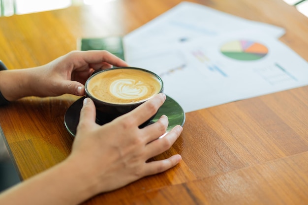 Closeup hand drinking hot coffee with working relax time