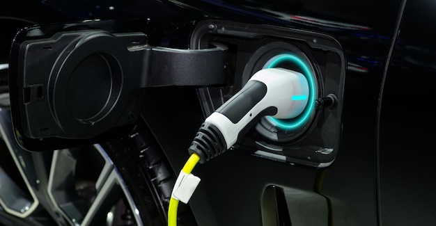 Closeup hand grip plug connected with socket  charge on black EV car for rechargeable battery