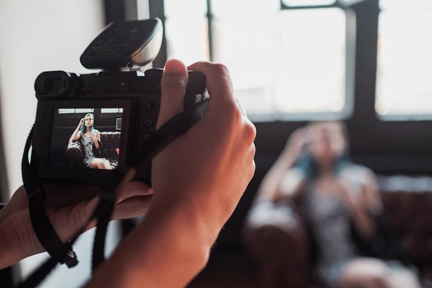 Крупный план руки с камерой Беззеркальная камера крупным планом в руке молодого человека на фоне студии Репортер делает снимок, фотограф смотрит в камеру