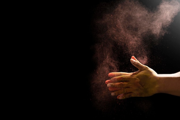 Closeup of hand holding colorful holi powder isolated over black background