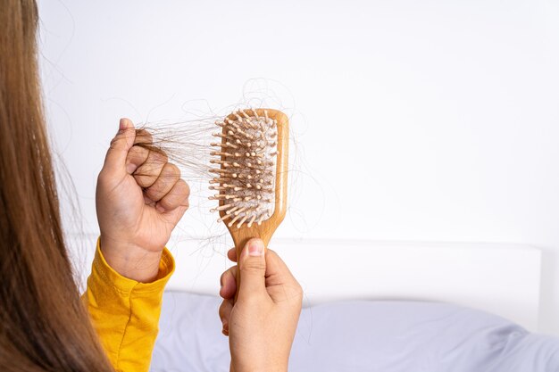 Primo piano mano che tiene pettine e problema di caduta dei capelli.