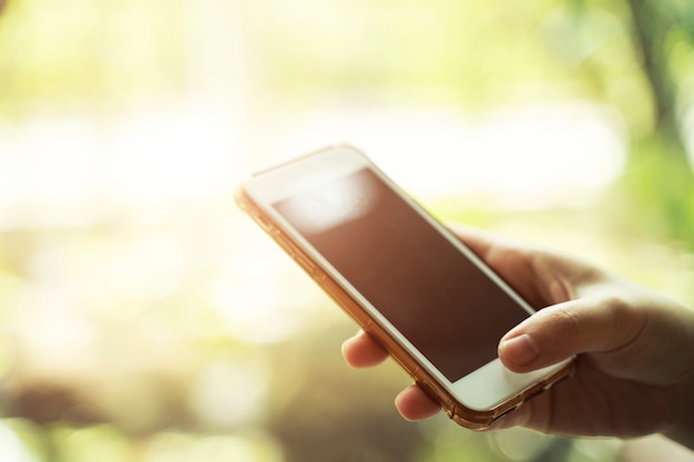 Closeup of hand holding mobile with sunlight. Technology and business concept.