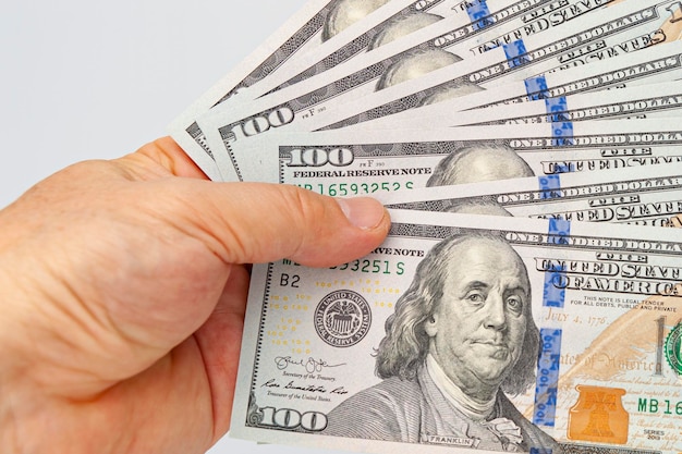 Closeup of hand holding nine us one hundred dollar bill isolated on white background