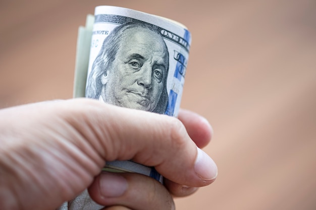 Closeup of hand holding Roll of US dollar banknote for paying someone