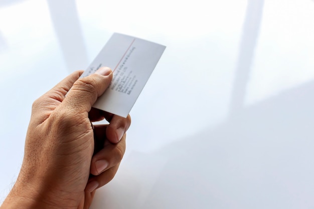 Closeup hand of a man hold business card with soft-focus and over light in the background