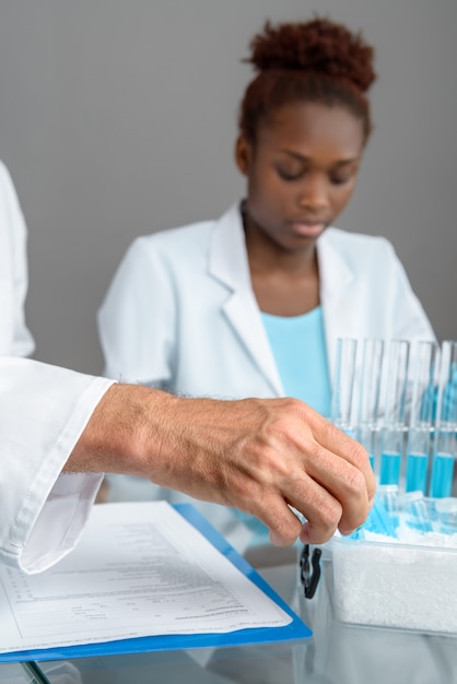 Closeup on a hand picking up scientific sample, African tech or scientist working with test tubes