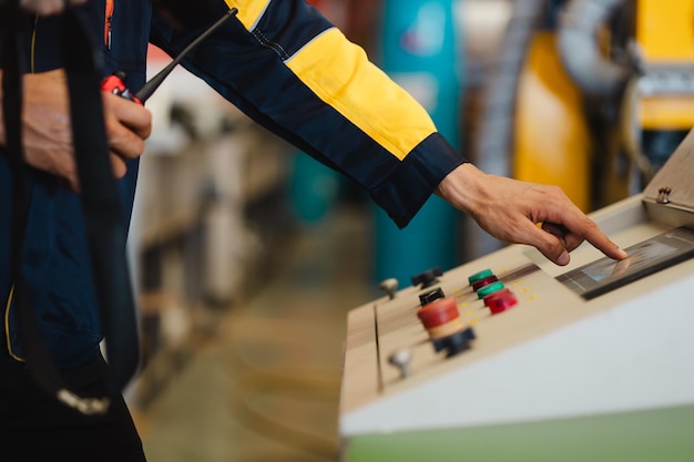 Closeup hand pressing power button on industrial manufacturing machine control panel
