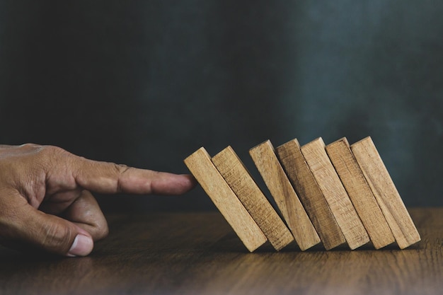 Foto hand closeup prevenire blocchi di legno che non cadono concetti di domino di gestione del rischio finanziario e pianificazione strategica e piano di sfida aziendale