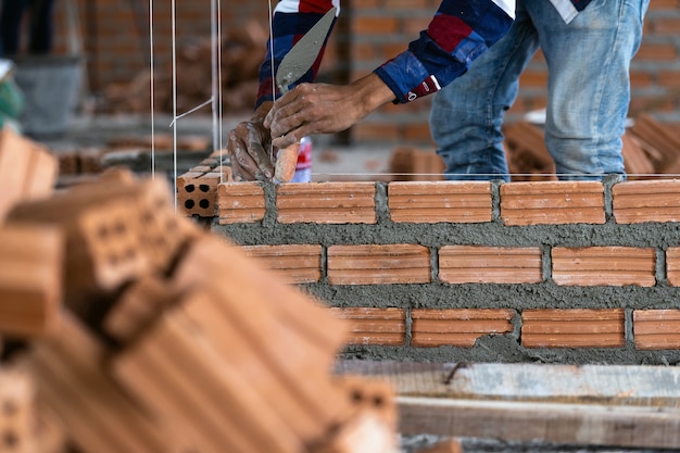 Closeup hand professional construction worker laying bricks in new industrial site