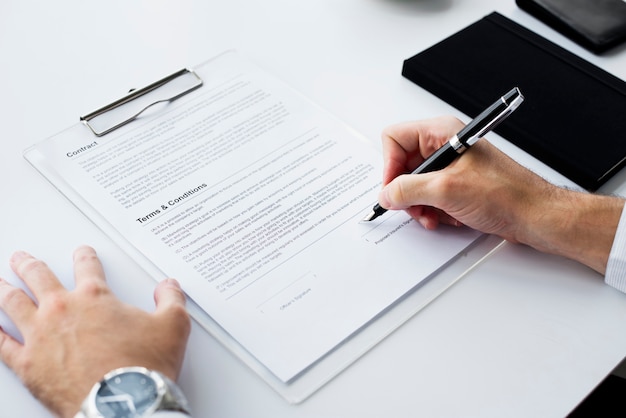 Photo closeup of hand signing paper workspace